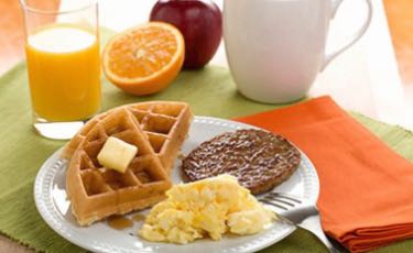 Waffles, eggs, and sausage breakfast. 