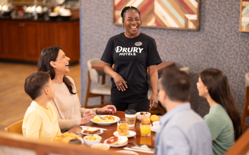 Family eating Hot breakfast and laughing with a breakfast attendant 
